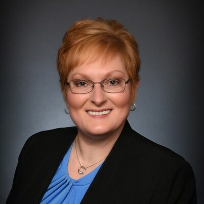 Smiling person with glasses and short hair.