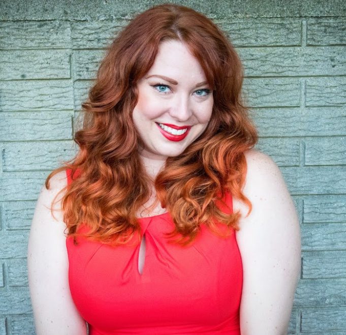 Woman with curly hair against brick wall.